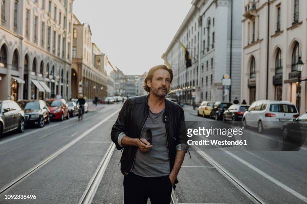 man wearing leather jacket walking in the street, munich, germany - männer über 40 stock-fotos und bilder
