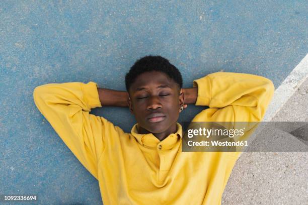 young black man sleeping on floor, with hands behind head - hands behind head stock pictures, royalty-free photos & images
