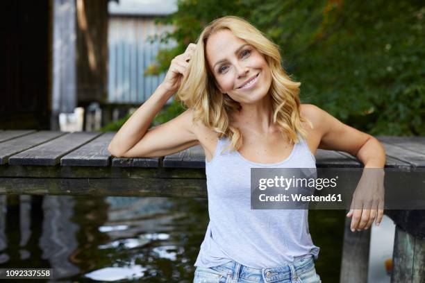 smiling relaxed woman at wooden jetty at a lake - beautiful mature woman stock pictures, royalty-free photos & images