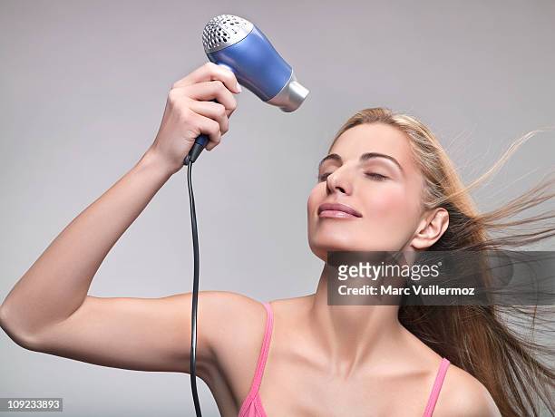 young woman using hair dryer - hair dryer fotografías e imágenes de stock