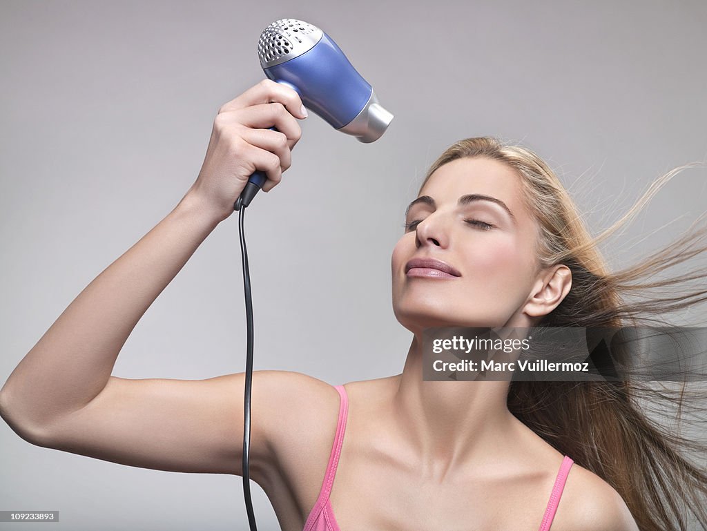 Young woman using hair dryer