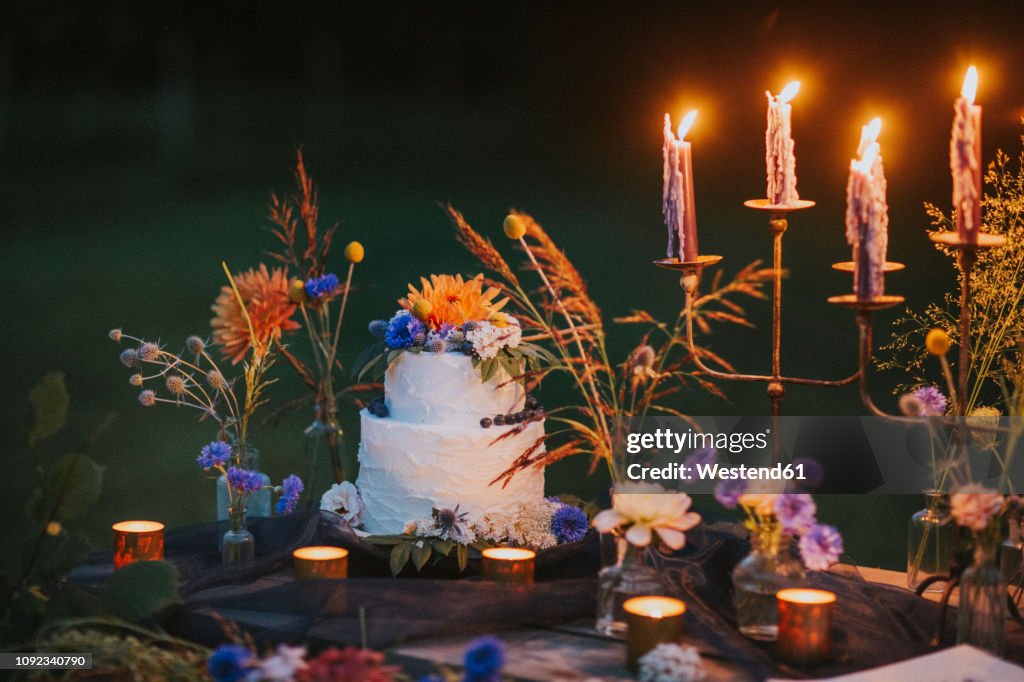 Wedding cake on table with candles outdoors