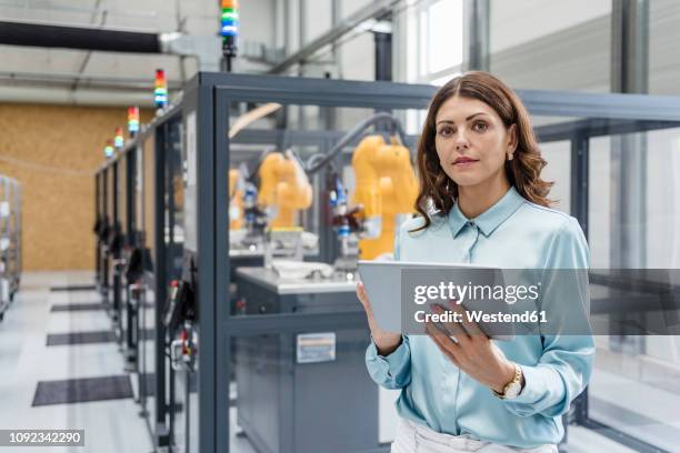 businesswoman in high tech company controlling industrial robots, using digital tablet - my tablet tool stock-fotos und bilder