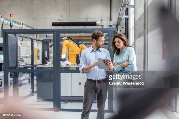 colleagues in high tech company controlling industrial robots, using digital tablet - conformity stock pictures, royalty-free photos & images