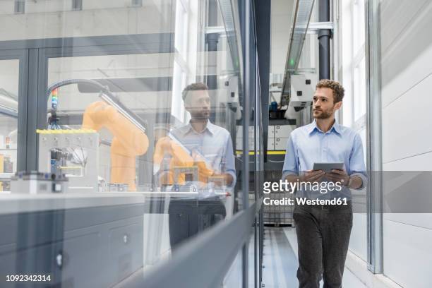 businessman checking robots with digital tablet in high tech company - herstellendes gewerbe stock-fotos und bilder