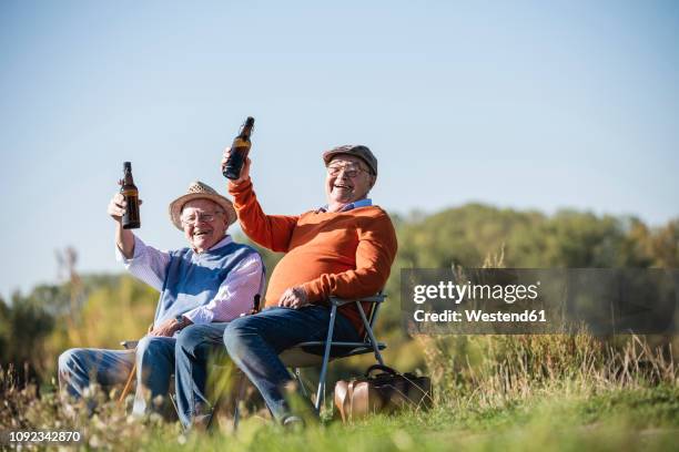 two old friends sitting in the fields, drinking beer, talking about old times - beers cheers stock pictures, royalty-free photos & images