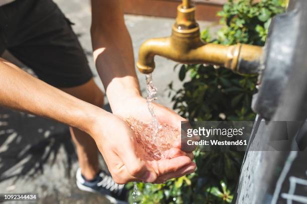 close up on hands and water spilling from a public fountain - fountain stock pictures, royalty-free photos & images