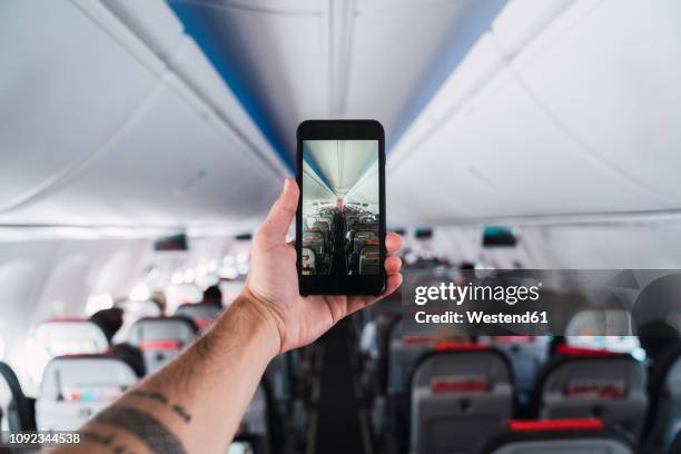 airplane, man using smartphone, taking a picture interior - salazar bronwich testify at hearing on re organization of mms stockfoto's en -beelden