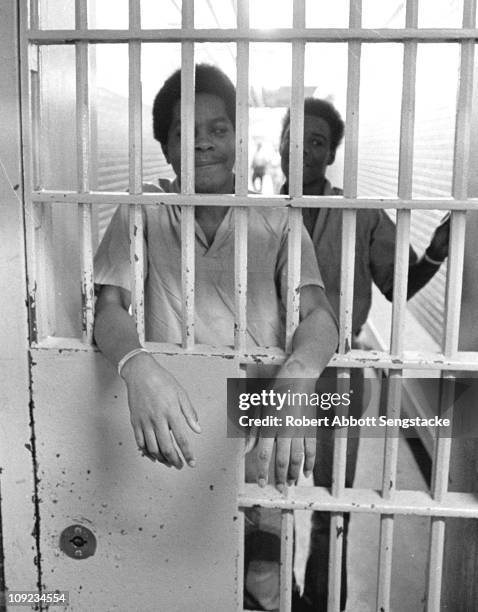 Inmates at the Cook County Jail look out from behind the bars of their cell, Chicago, IL, 1972.