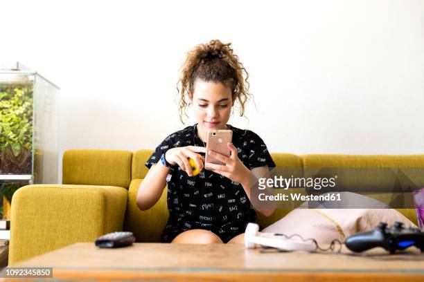 portrait of girl sitting on the couch at home using smartphone - 12 13 years stock pictures, royalty-free photos & images