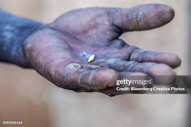 an artisanal miner displays a small piece of gold - mijnwerker stockfoto's en -beelden