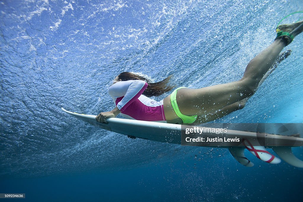 Female surf duck diving under a large wave.