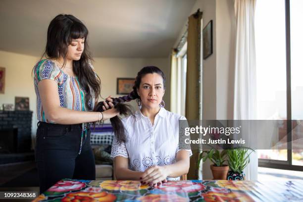 two millennial latina girlfriends relaxing at home braiding hair - bad colleague stock pictures, royalty-free photos & images