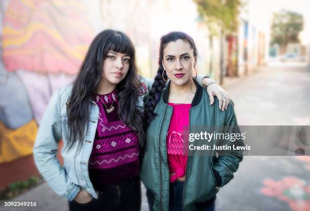 two millennial latina girlfriends walking along alley with mural in background - stern gold stock pictures, royalty-free photos & images