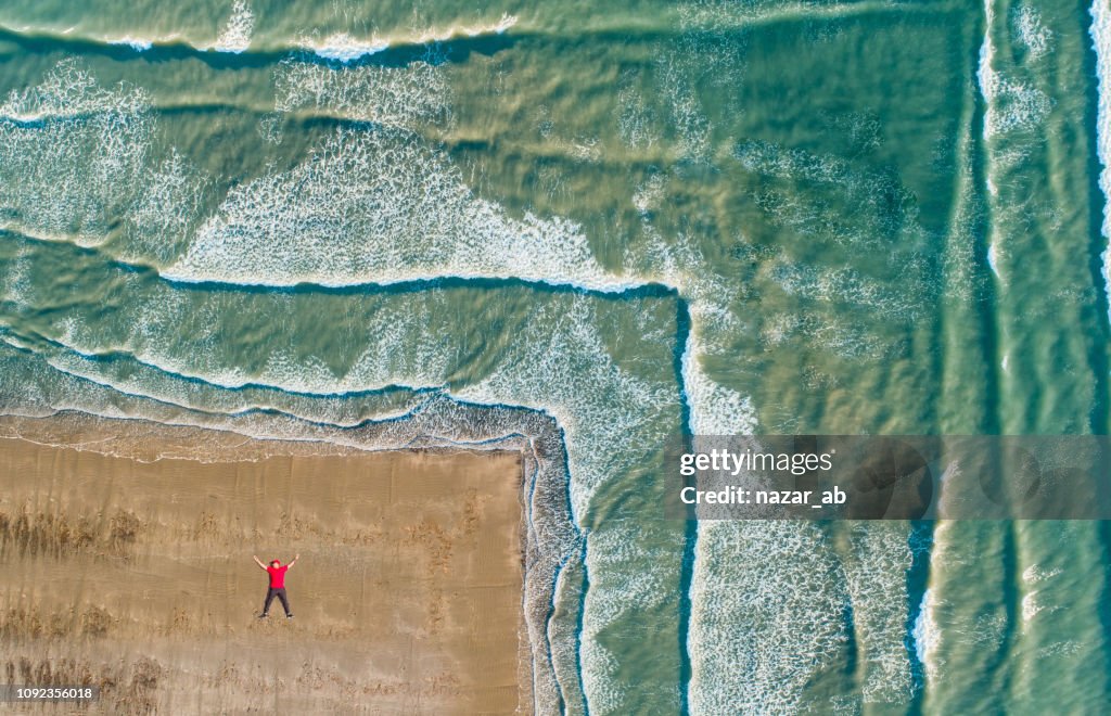 Aerial view of man lying on beach.