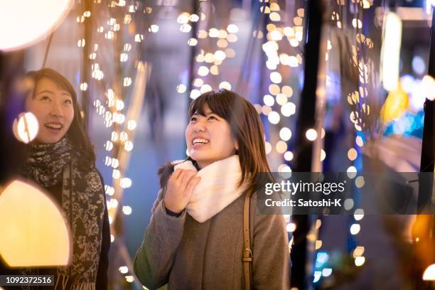 junge freundinnen genießen weihnachtsbeleuchtung - japanese bussiness woman looking up stock-fotos und bilder