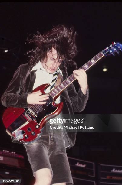 Perform on stage at the Lyceum, London, July 1976, Angus Young.