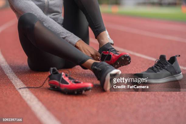 athlete changes into her track shoes on a stadium field - studded stock pictures, royalty-free photos & images