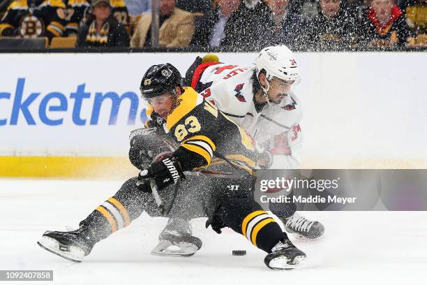 Jonas Siegenthaler of the Washington Capitals commits a holding foul against Brad Marchand of the Boston Bruins during the first period at TD Garden...