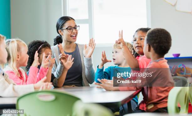 maestra de preescolar multiétnica y los estudiantes en el aula - showing fotografías e imágenes de stock