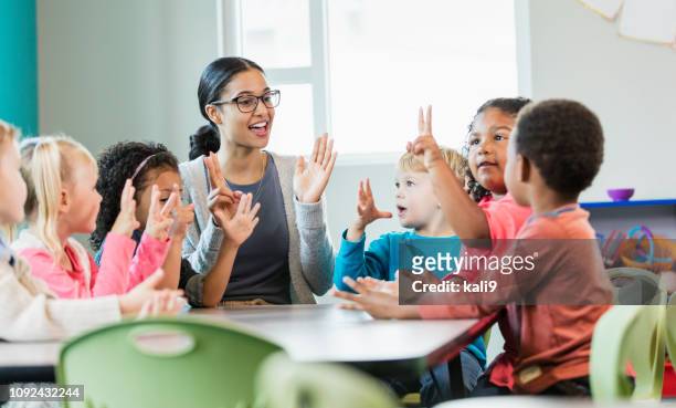 multi-ethnic preschool teacher and students in classroom - preschool stock pictures, royalty-free photos & images