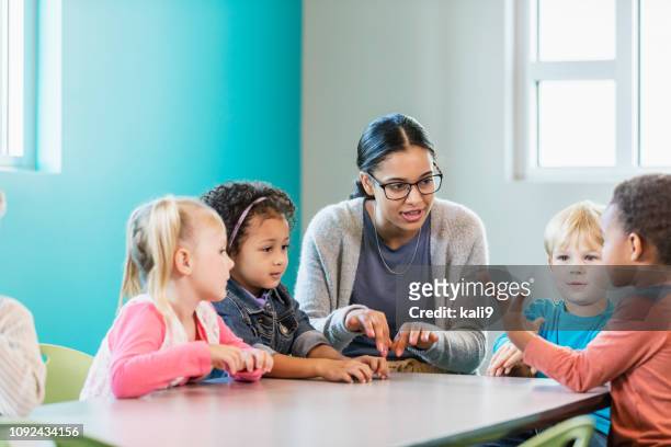 multi-etnische preschool leraar en leerlingen in klas - foundation conversations story of a girl stockfoto's en -beelden