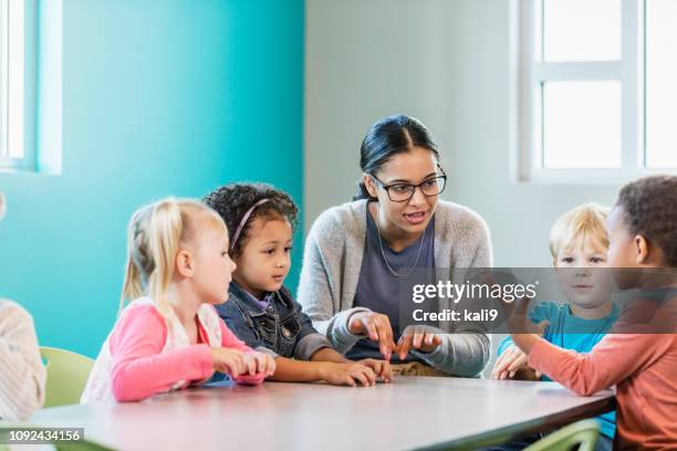 multi-ethnic preschool teacher and students in classroom - listening conversation stock pictures, royalty-free photos & images