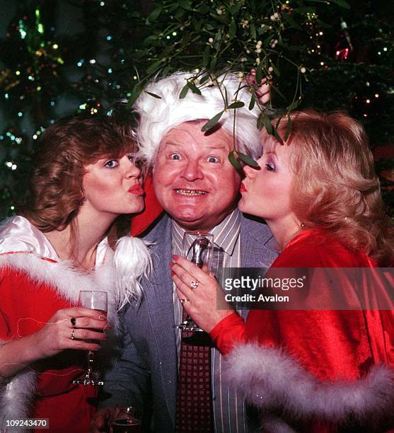 British Comedian and Writer Benny Hill Being kissed under the mistletoe by two of his 'Hill's Angels' Left: LESLEY WOODS and Right: SUE UPTON, .