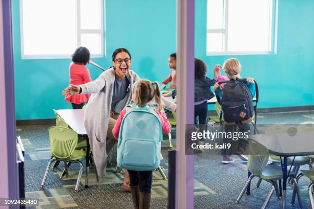preschool teacher in classroom greeting students - arrival hug stock pictures, royalty-free photos & images