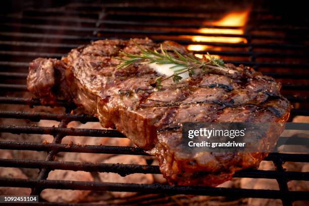grote sappige rundvlees rib eye steak op een hete grill met houtskool en vlammen - rib eye steak stockfoto's en -beelden