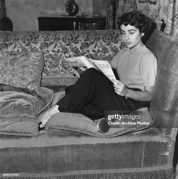 British-born actress Elizabeth Taylor reads a copy of 'Look' magazine, 1949.