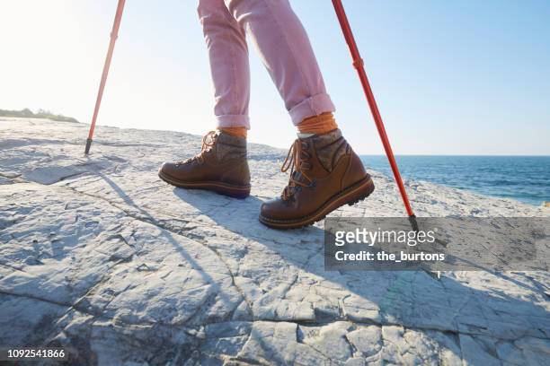 woman in hiking boots walking on a rock by the sea - leather training shoes stock-fotos und bilder