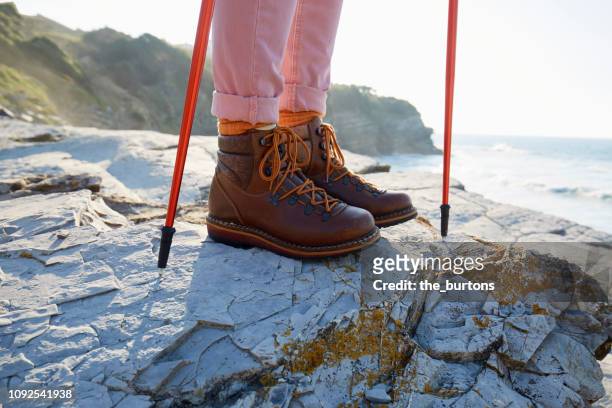 woman in hiking boots standing on a rock by the sea - leather training shoes stock-fotos und bilder