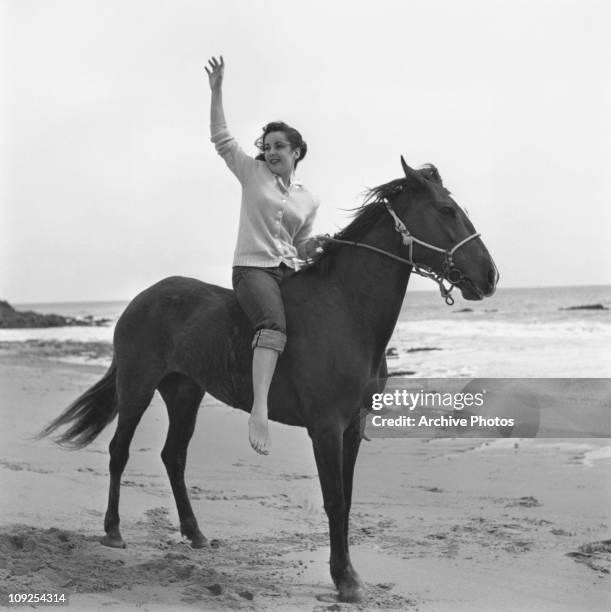 British-born actress Elizabeth Taylor on horseback on a beach, circa 1949.