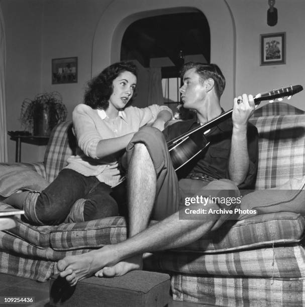 British-born actress Elizabeth Taylor listens to her friend, actor Marshall Thompson , playing the guitar, circa 1948.