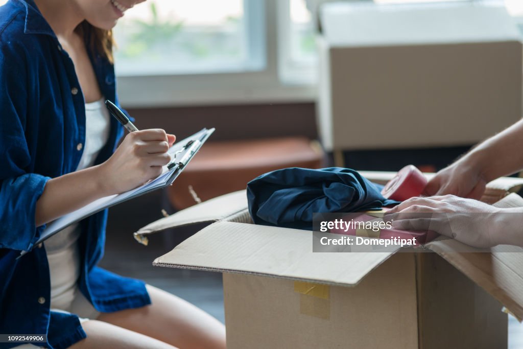 Jong (echt) paar verpakking en spullen controleren met behulp van checklist voordat hij naar de nieuwe verblijfplaats.