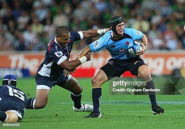 Berrick Barnes of the Waratahs holds off the Rebels defence during the round one Super Rugby match between the Melbourne Rebels and the Waratahs at...