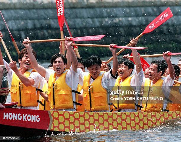 Japanese rowers raise their oars after winning the preliminary race of the Yokohama Chinatown Cup Dragon Boat race for the anniversary festival of...