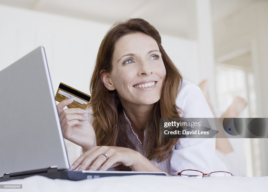 Woman using laptop holding credit card