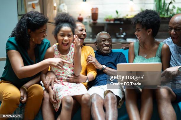 afrikanische hispanische familie zusammen zu hause während einer von ihnen benutze laptop --mehrgenerationen familie - brazilian family stock-fotos und bilder