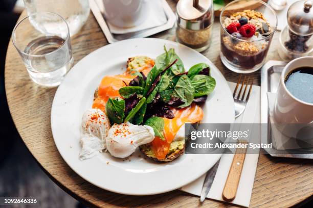 close up of healthy breakfast with avocado on toast, poached egg and spinach - zalm gerecht stockfoto's en -beelden