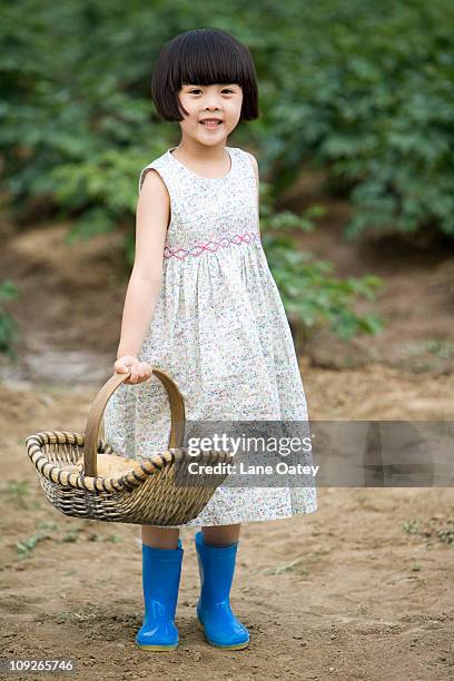 little girl holding basket in farm - wellington boots stock pictures, royalty-free photos & images