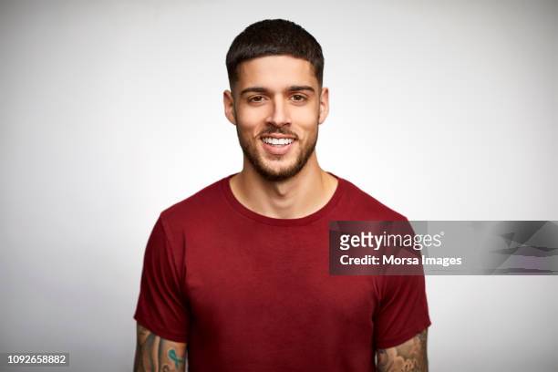 portrait of smiling young man wearing t-shirt - young men stock pictures, royalty-free photos & images