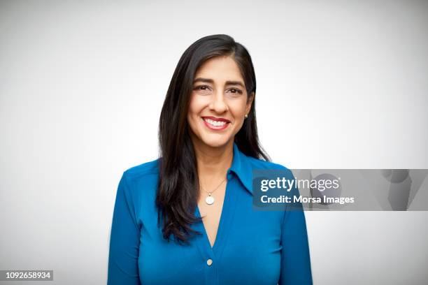 portrait of smiling mid adult woman on white - hispanic woman stockfoto's en -beelden