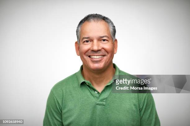 portrait of mature man smiling against white - lateinamerikaner oder hispanic stock-fotos und bilder
