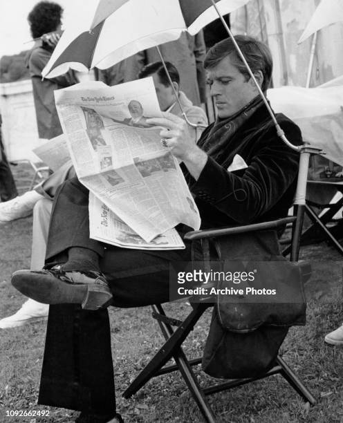 American actor Robert Redford reading 'The New York Times' on the set of the Paramount Pictures film 'The Great Gatsby', for which he is still in...