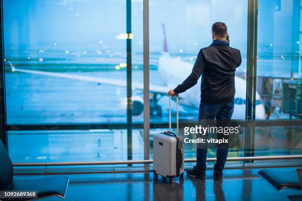man talking on cell phone at the airport - airport zurich imagens e fotografias de stock