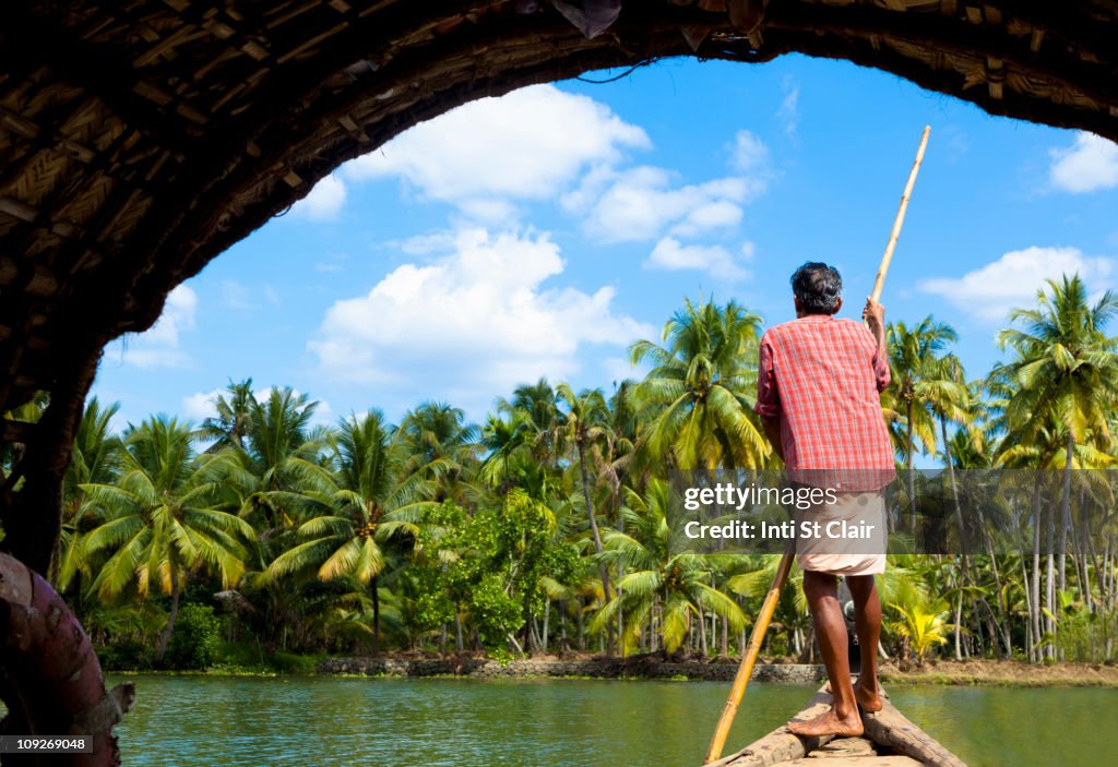 Man standing in boat on tranquil forest river