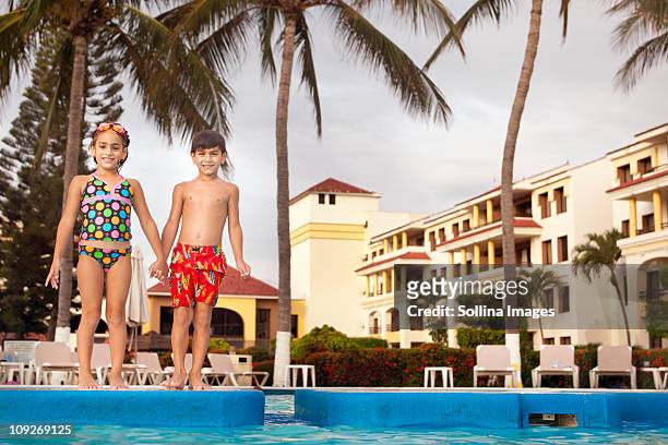 brother and sister standing at resort poolside holding hands - hot mexican girls stock pictures, royalty-free photos & images