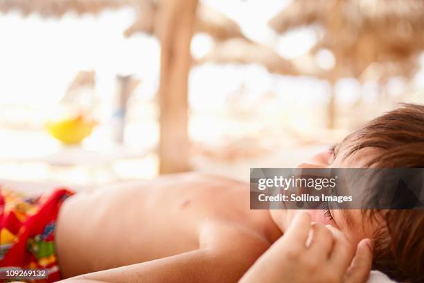 sleeping mixed race boy laying on beach - heat exhaustion stock pictures, royalty-free photos & images